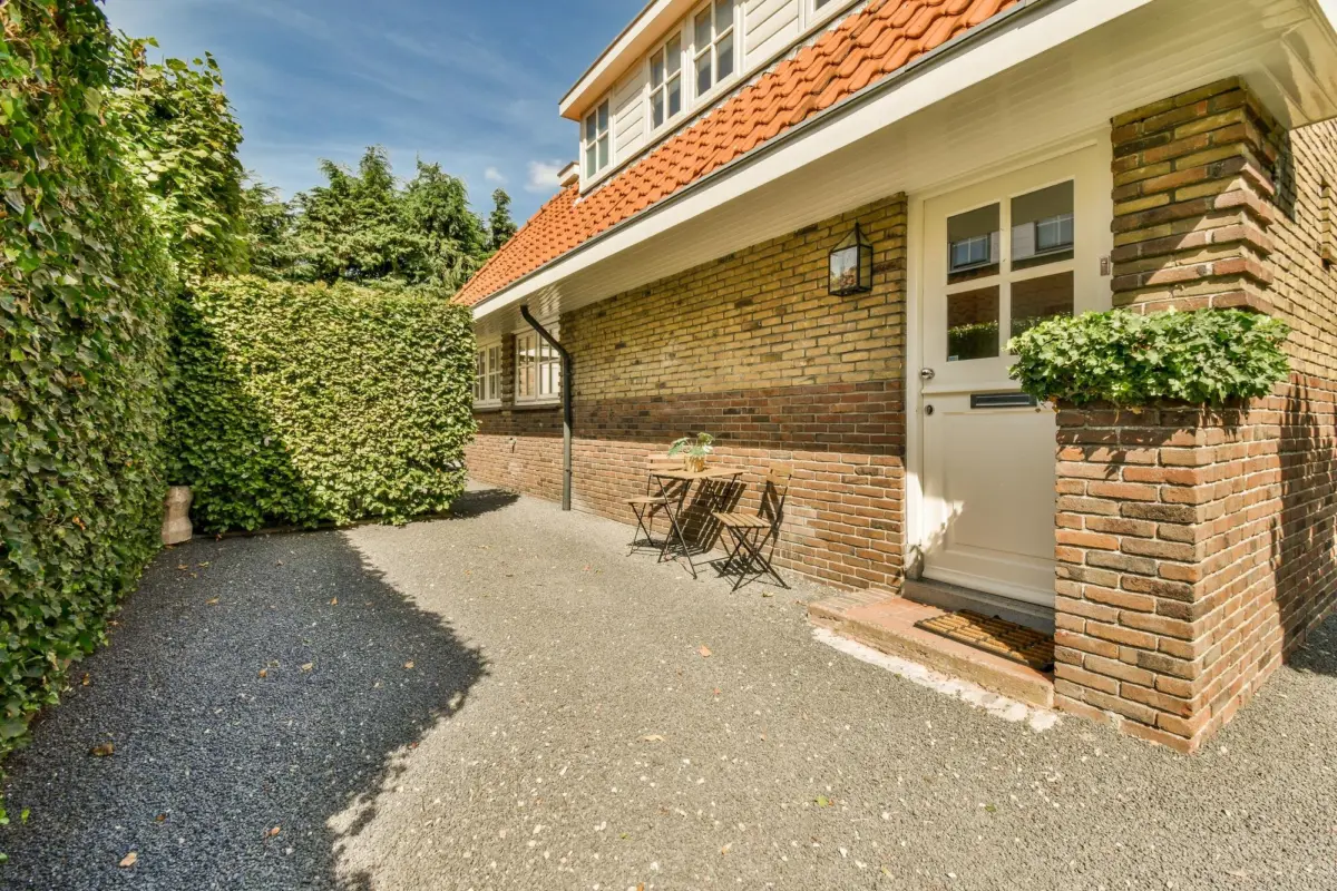 Einfamilienhaus aus Klinker mit Ziegeldach, Terrasse mit Sitzplatz und hoher Hecke