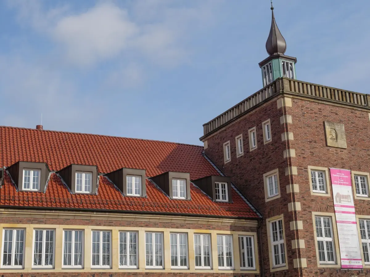 Backsteingebäude mit rotem Ziegeldach und Turm mit Zwiebelhaube